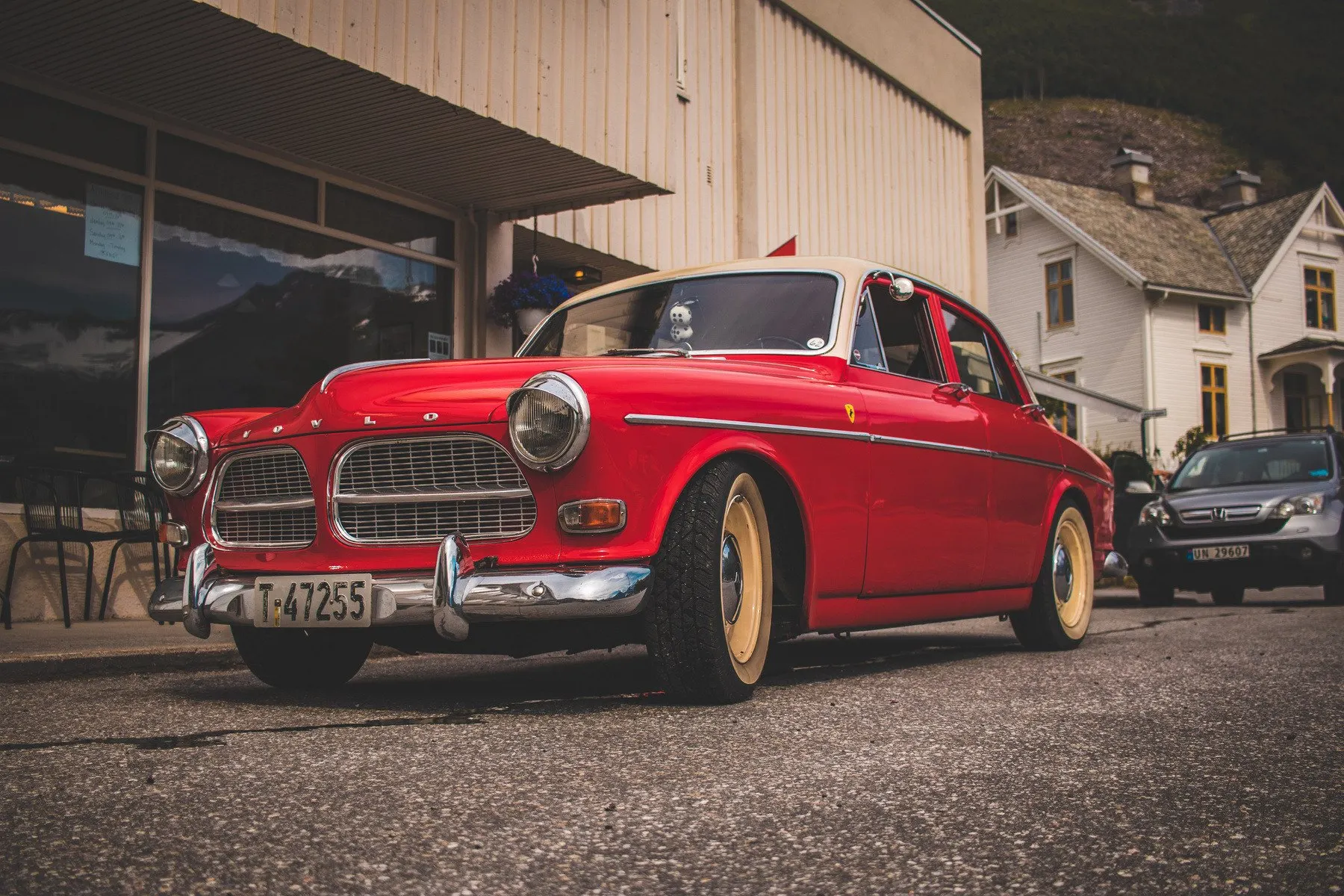 Rode Volvo Amazon uit 1967 geparkeerd voor een houten gebouw