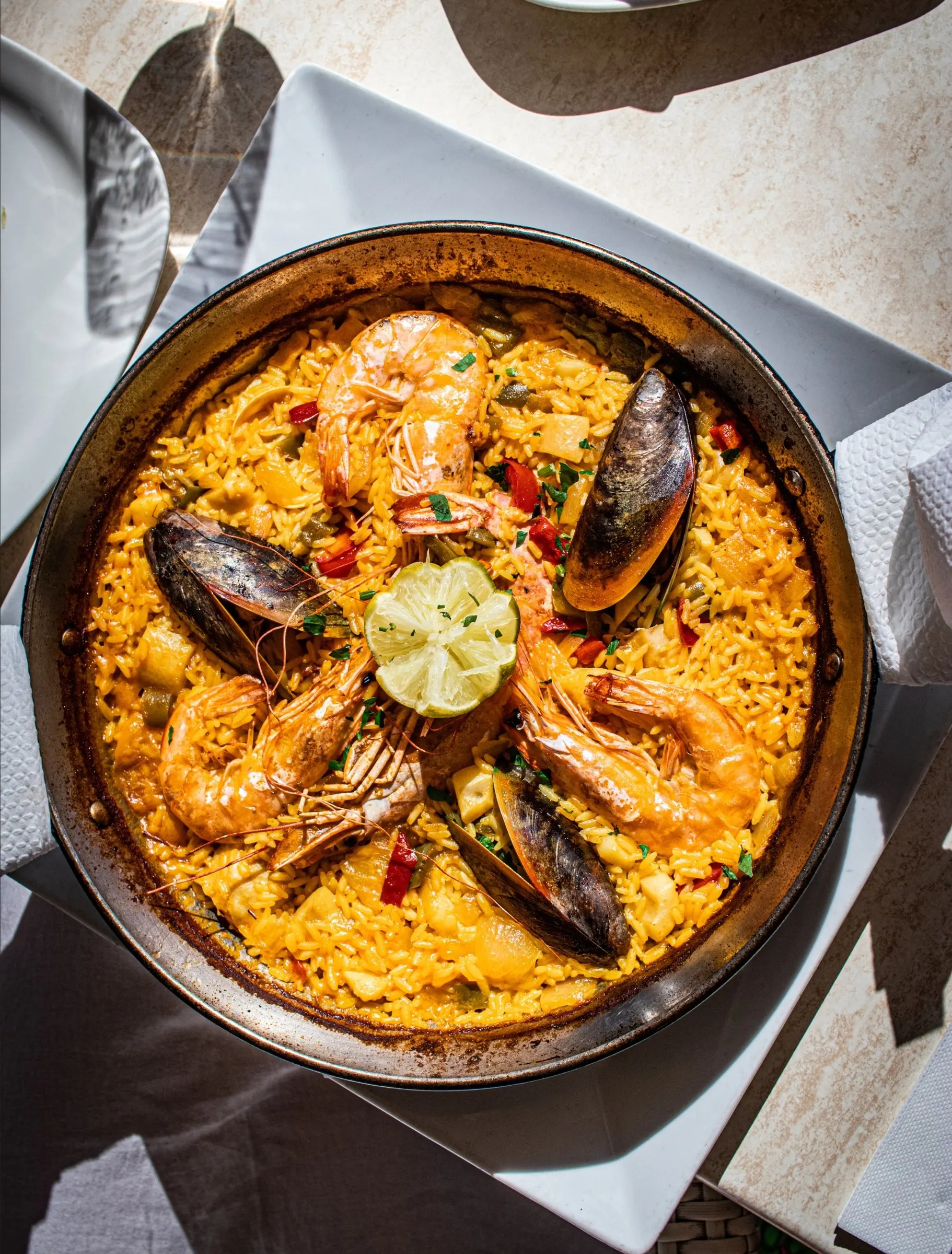 Paella met gamba's, mosselen en een partje limoen, van bovenaf gefotografeerd